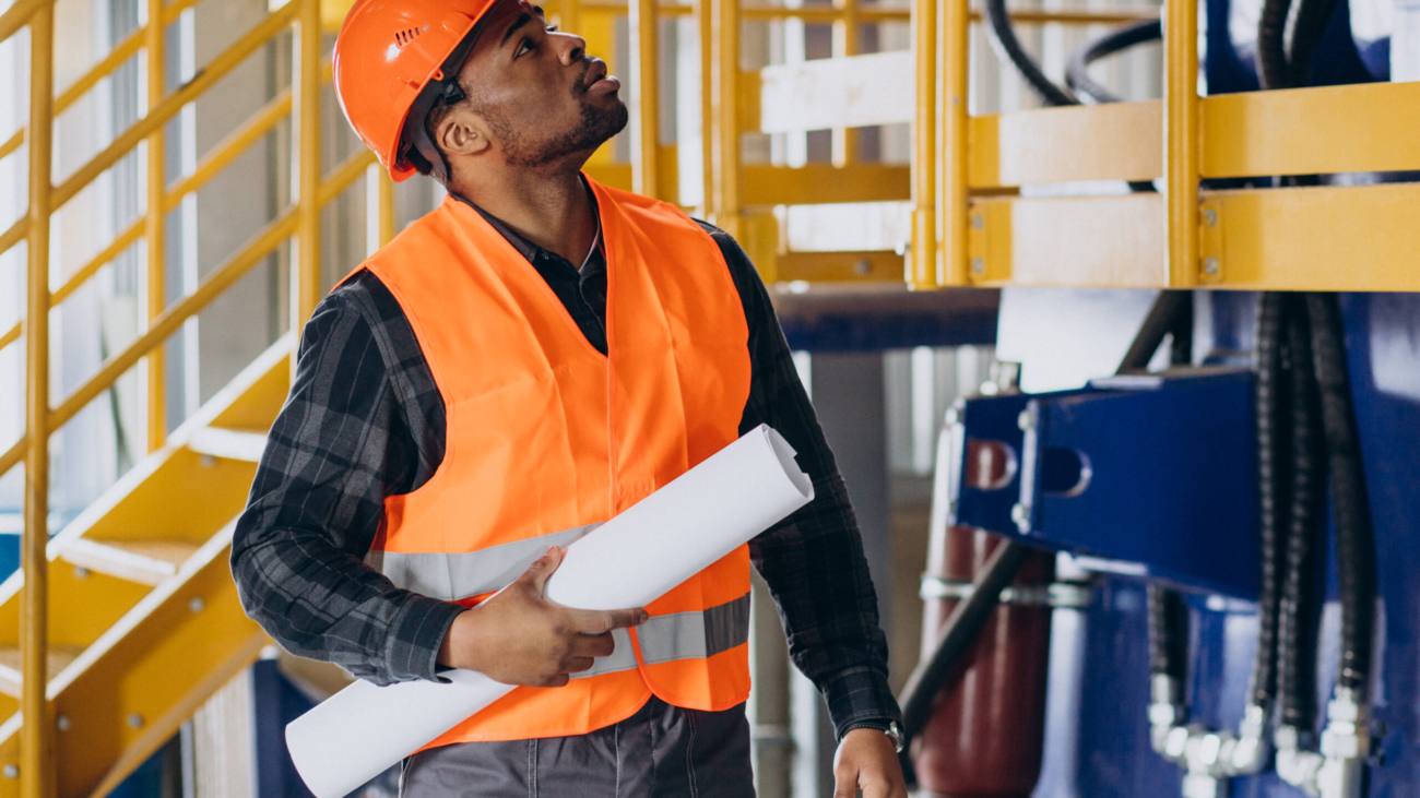 African american worker standing in uniform wearing a safety hat in a factory